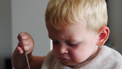 Cute-caucasian-toddler-little-boy-with-blond-hair-eating,-closeup-on-face