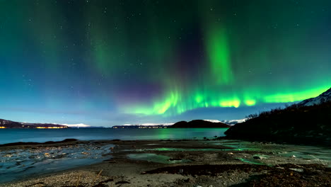 timelapse view from norwegian arctic beach as green aurora borealis dance in sky