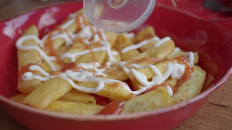 close up of french fries with ketchup and mayonnaise in a red bowl