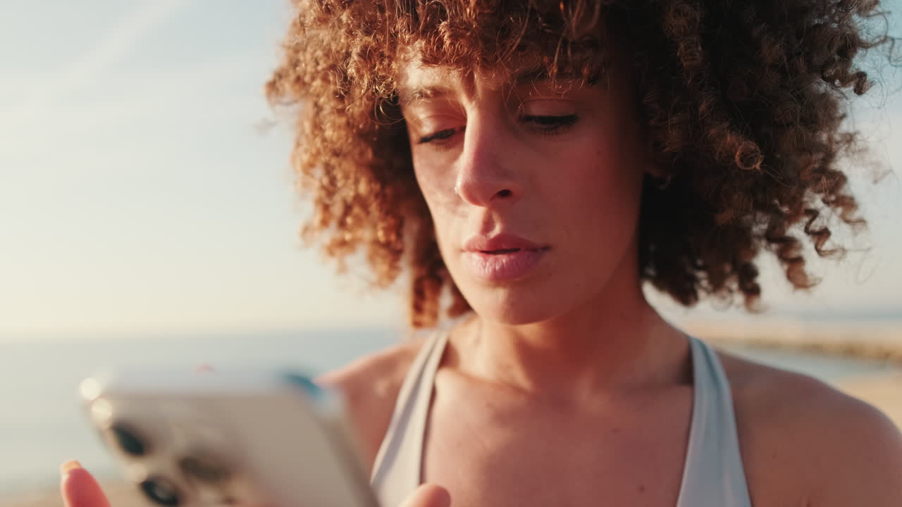 Woman Checks Fitness on Phone at Beach