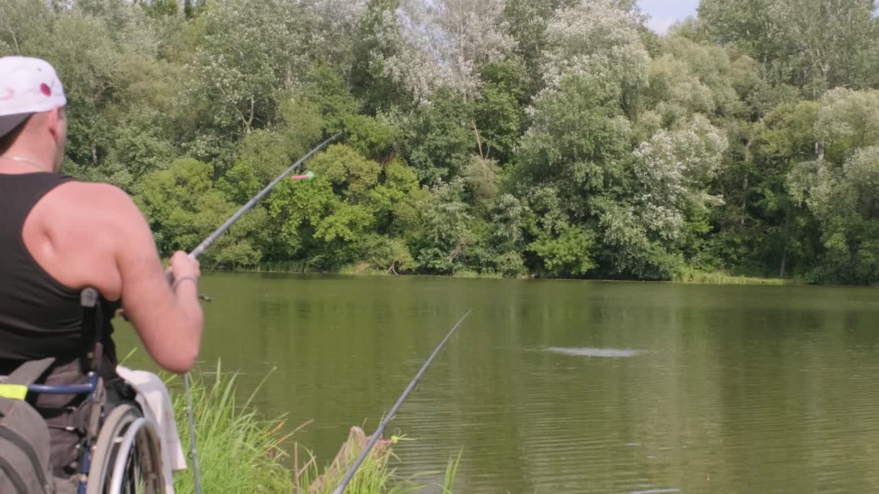 Pria penyandang disabilitas memancing di danau. Kursi roda. Berkemah. Musim panas.