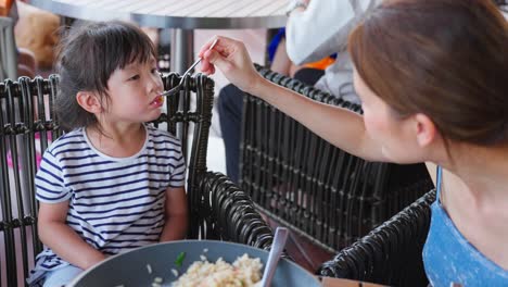 mother feeding her daughter lunch at a cafe