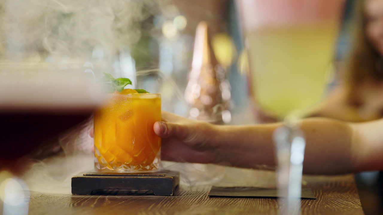 Barman che stappa un cocktail presentato con nebbia per un cliente.