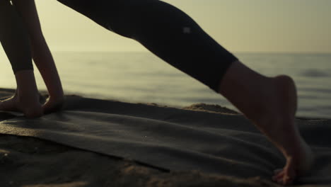 sporty woman feet exercising on sand closeup. girl practicing yoga at sunrise.