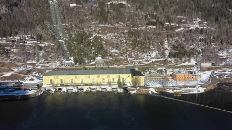 nore i hydroelectric powerplant operated by statkraft in rodberg norway - sideways moving sunny day aerial overview with pipelines coming down hillside in background