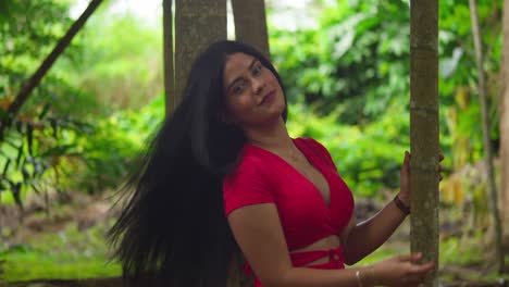 beautiful woman in red dress posing in lush tropical forest