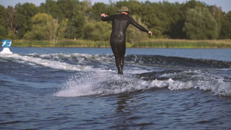 surfer surfing longboard in wave with cross step and nose ride behind a boat in slow motion