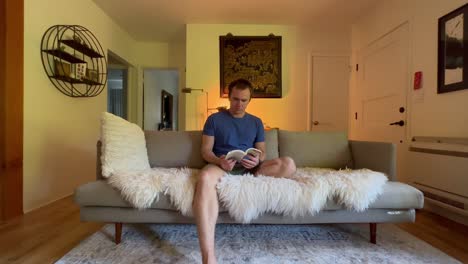 a man sits in his apartment reading a book relaxingly