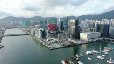 área-De-La-Bahía-De-Hong-Kong-Kowloon-Con-Rascacielos-De-La-Ciudad-Y-Nuevo-Edificio-Del-Hospital-Infantil-Durante-La-Construcción,-Vista-Aérea