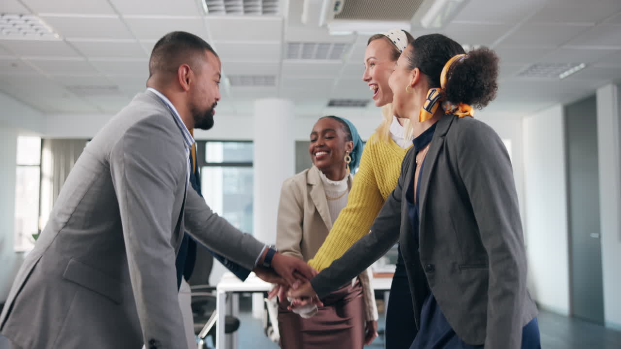 Diverse business team celebrating success with hands together in office
