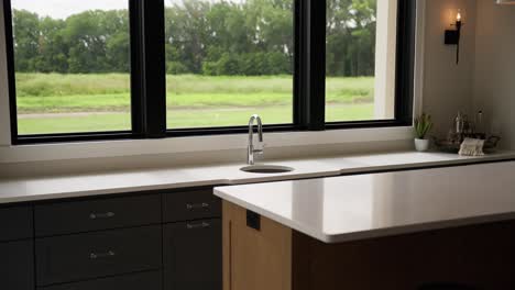 Medium-tight-shot-of-a-clean-white-bar-sink-with-sleek-silver-faucet,-bathed-in-natural-light-from-windows