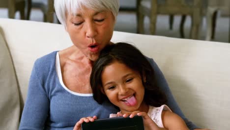 granddaughter and grandmother taking selfie on mobile phone in living room