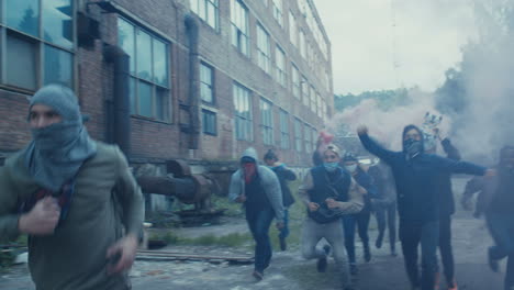 jóvenes multiétnicos armados con bufandas en la cara corriendo y atacando en barrios marginales