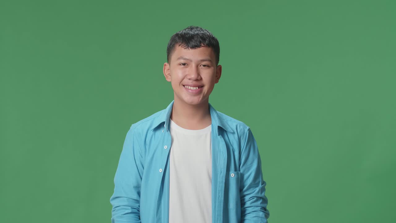 Young Asian Boy Warmly Smiling On Green Screen Background In The Studio