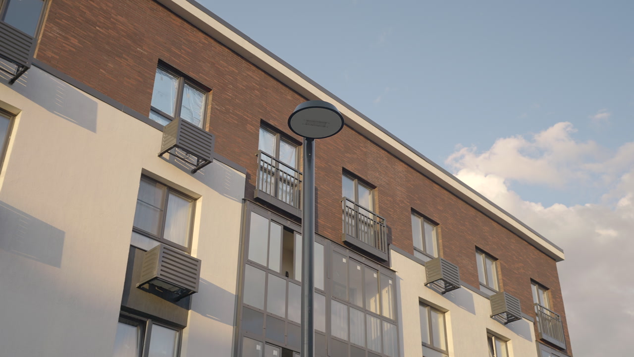 Round Lamp Head Under Pastel Sky, Tall Pole Rising Beside Brick And Glass Apartment Balconies At Golden Hour