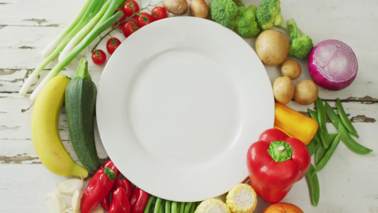 video de frutas y verduras frescas alrededor de una placa blanca con espacio de copia en un fondo de madera