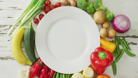 Video-of-fresh-fruit-and-vegetables-around-white-plate-with-copy-space-on-wooden-background