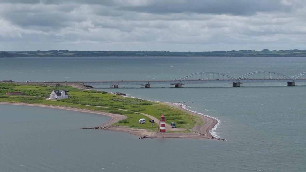 Riprese aeree con teleobiettivo che circondano il faro di Griseta Odde, mostrando le acque tranquille del Limfjord, la vegetazione costiera e il pittoresco litorale di Oddesund