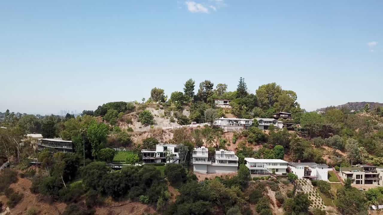 Noble villas on hillside of Pasadena, Los Angeles at sunny day. Aerial lateral wide shot. Palm trees and plants on mountains of USA. Blue sky and sunny day in California