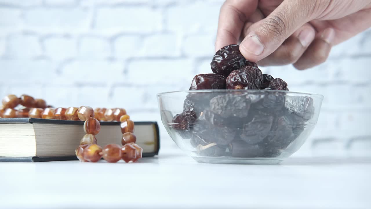 hand pick fresh date fruit in a bowl and holy book of quran on table