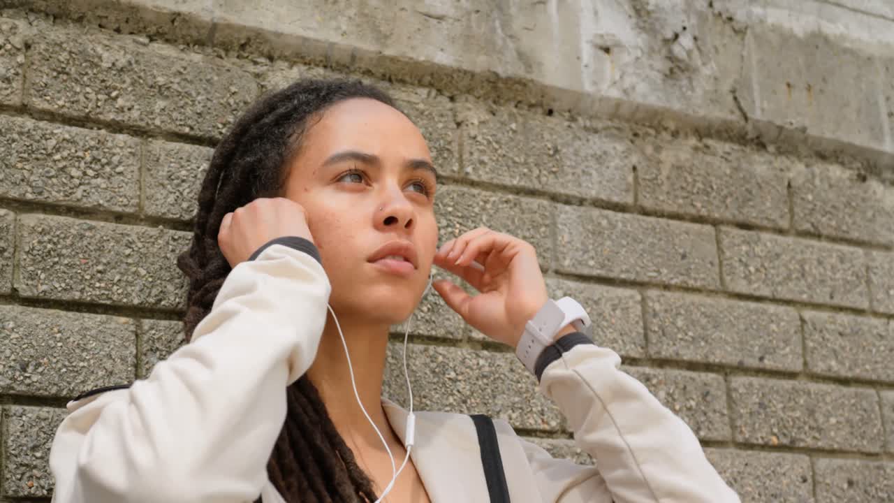 vista frontal de una joven mujer afroamericana con auriculares en la ciudad 4k