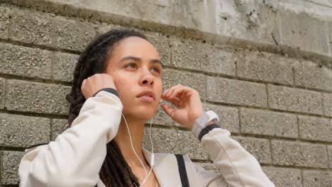 Vista-Frontal-De-Una-Joven-Afroamericana-Con-Auriculares-En-La-Ciudad-4k