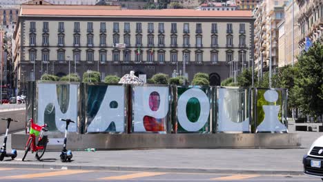 car passing by 'napoli' sign and hillside view