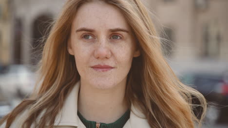 Red-Haired-Young-Woman-With-Freckles-Looks-Smiling-Directly-Into-The-Camera