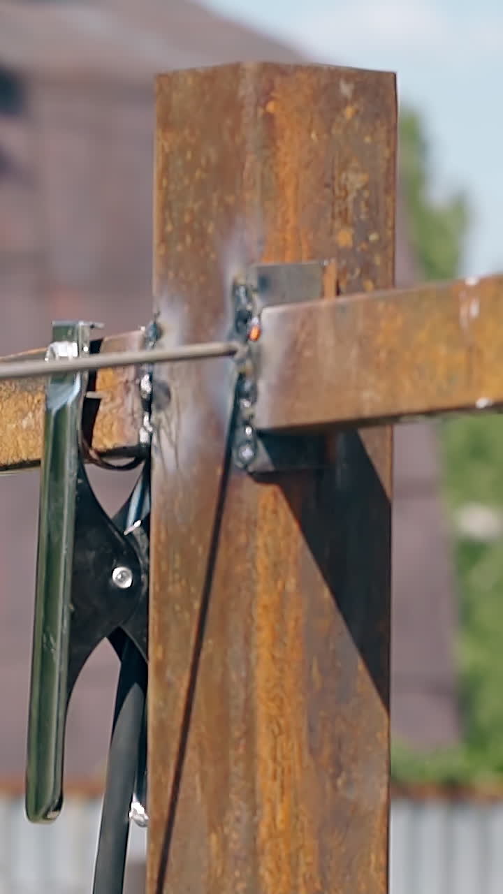 slow motion closeup worker in protective glove welds fence metal carcass with modern tool on day