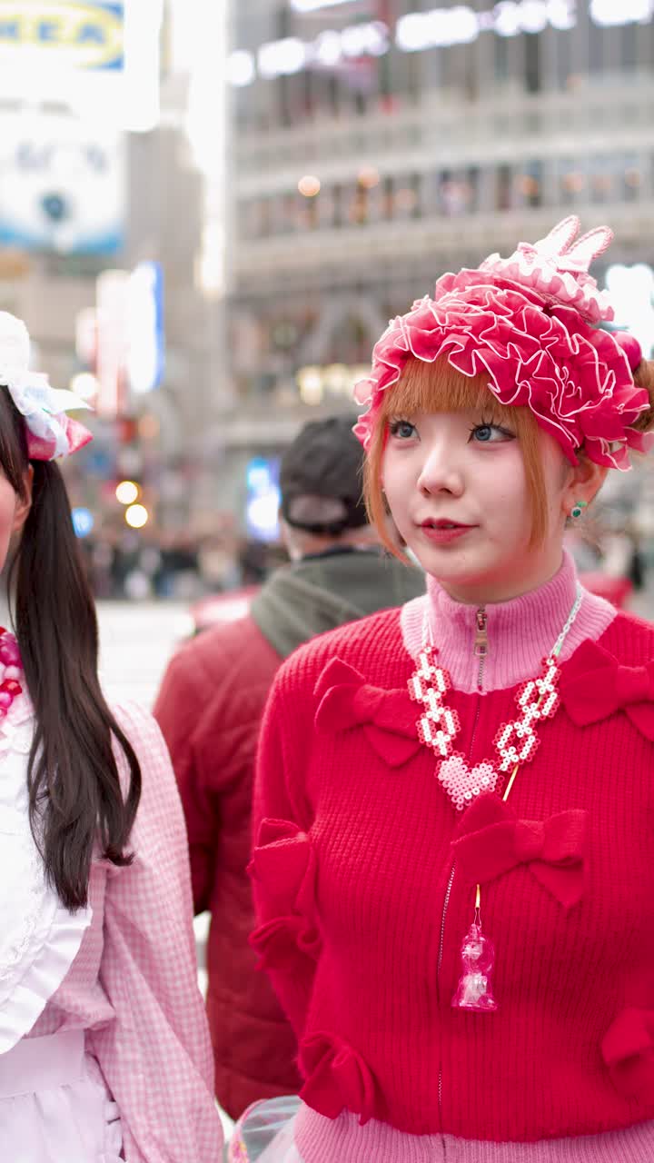 Due donne che indossano vivaci abiti moda street decora rosa e rossi ridono insieme a Shibuya.