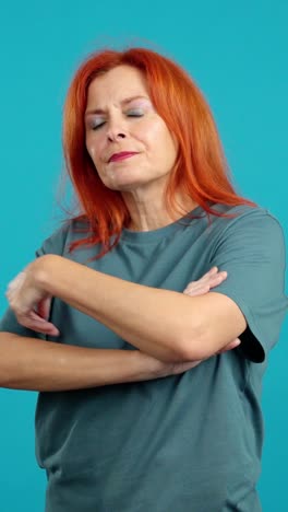 serious woman with red hair and crossed arms against a blue background