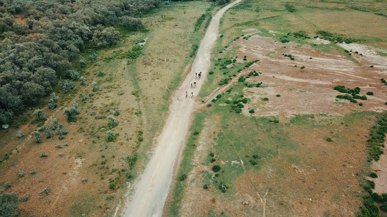 vista aérea de alejamiento de un grupo de ciclistas que viajan en un camino de tierra de kenia