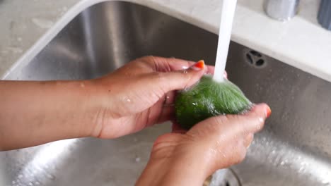 mujer lavando verduras verdes en el fregadero de la cocina