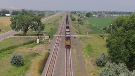 aerial following freight train down tracks parallel to highway