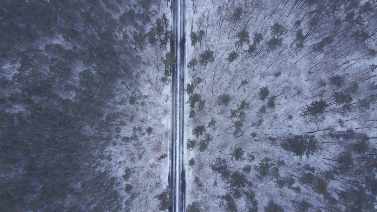 Fitta nevicata che ricopre un paesaggio di boschi e strade - ripresa aerea.