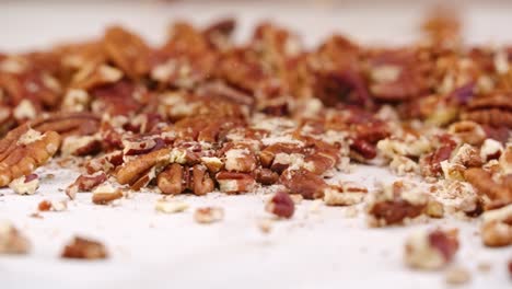 whole pecan nuts being broken into tiny crushed pieces by mallet in slow motion