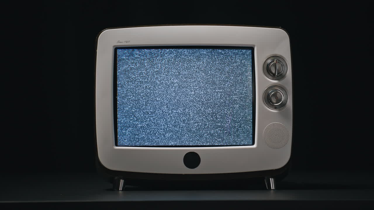 Primo piano di una mano che accende la TV con effetto flicker su un vecchio schermo in una stanza buia. CRT retrò