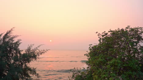 A-pan-across-incoming-ocean-waves-with-a-pink-and-purple-sunset