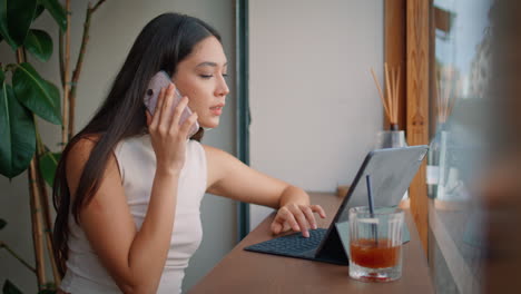 mujer hablando por teléfono y trabajando en un café