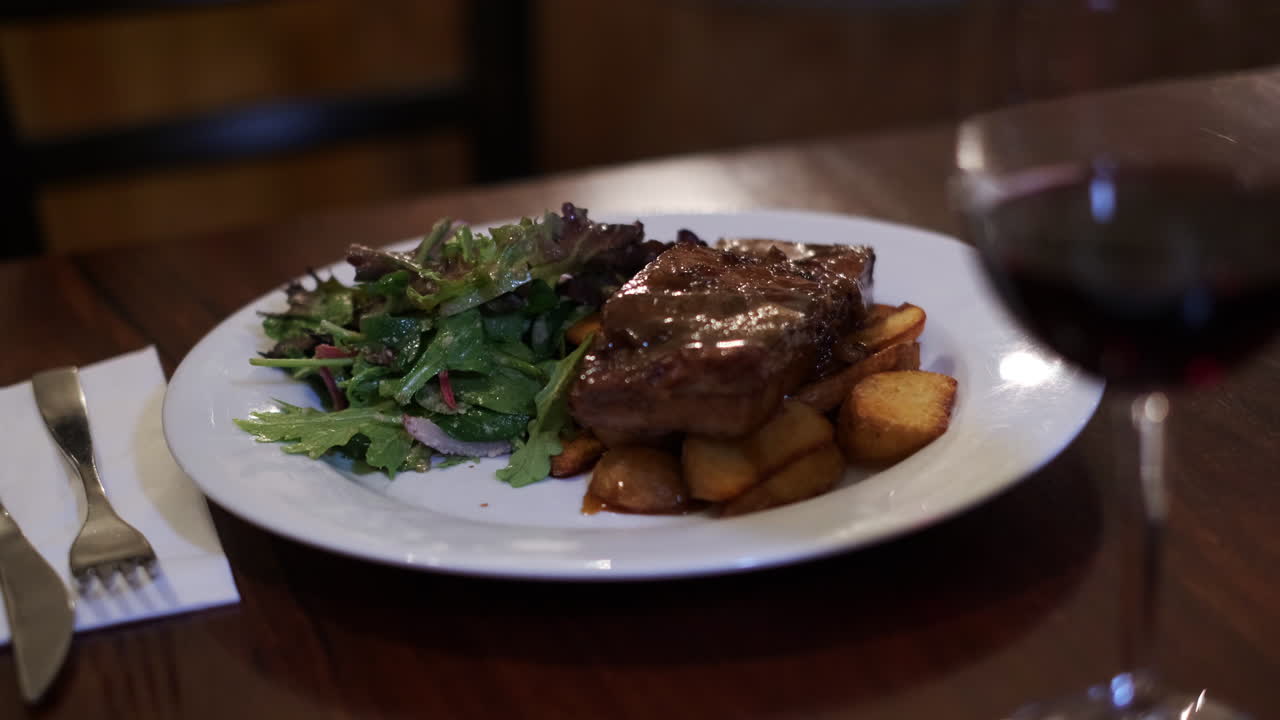 panceta de cerdo asada caramelizada con patatas asadas y ensalada en la mesa del restaurante