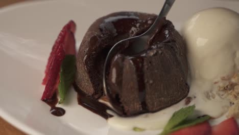 primer plano de la persona que come postre dulce gourmet con cuchara - volcán de chocolate y helado de vainilla