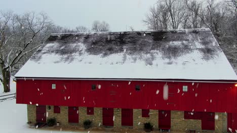 aerial reveal of red barn during snowstorm