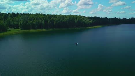 approaching drone view of paddleboarder on large dark lake