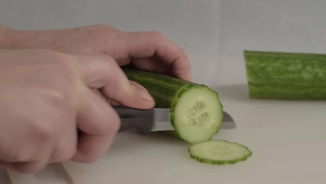 hand slicing a ripe cucumber with knife medium shot