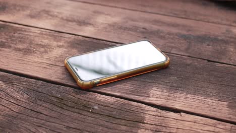 woman's hand holding a smartphone on a wooden table