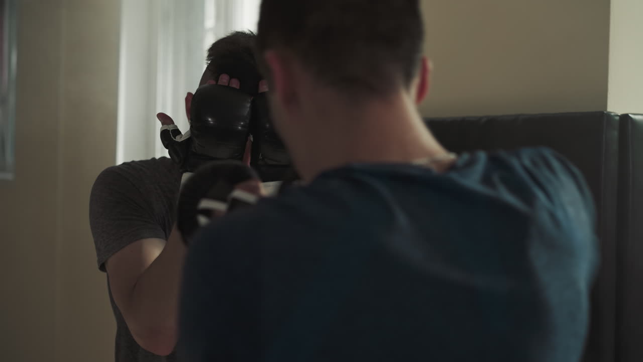 el boxeador bloquea la cara de los golpes durante el sparring en el gimnasio. los deportistas en pareja ejercitan técnicas de combate en el club de lucha a cámara lenta. batalla de socios