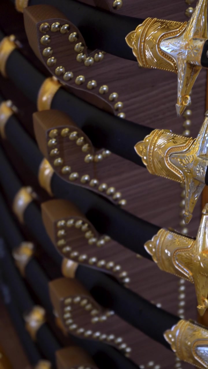 Dettaglio ravvicinato di intricate impugnature in oro e nero di spade cerimoniali tradizionali. Armi splendidamente lavorate preparate per un'autentica danza Khaleeji Ardah a Doha