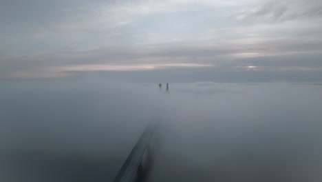 car starting trip in early foggy morning on bridge hiding in mist, aerial view