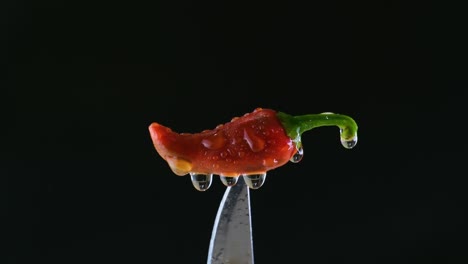 water mist on red chilli present on top of a knife with black background