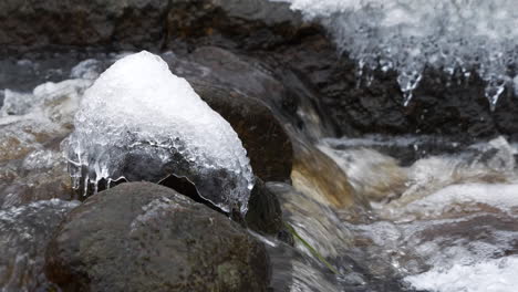 isolated icy rock in natural stream of water, slow motion